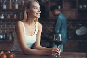 Mujer bonita bebiendo un poco de vino en casa en la cocina