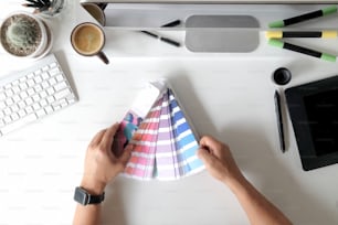 Graphic designer che lavora al progetto di disegno architettonico e campioni di colore, cartella colori sul posto di lavoro dello studio.