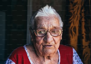 Retrato em preto e branco de uma velha mulher enrugada de cem anos de idade. Uma avó sorridente usando óculos grandes. Idade, bondade e sabedoria