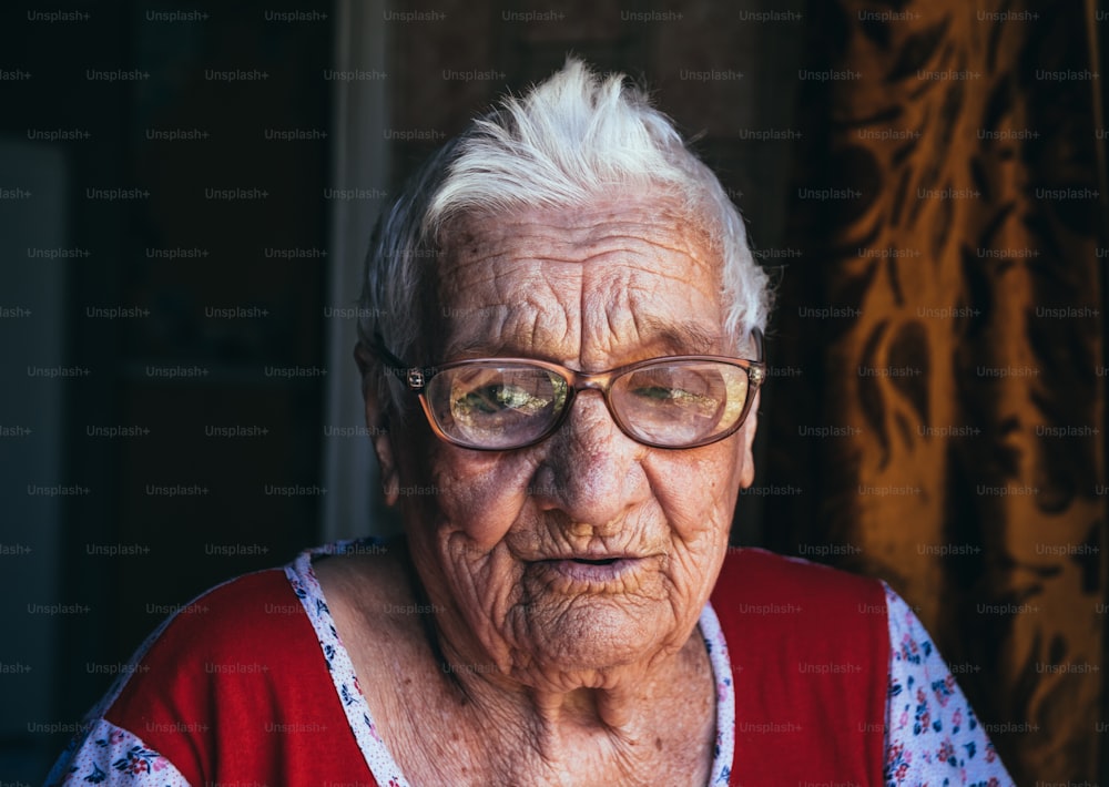 Ritratto in bianco e nero di una vecchia donna centenaria rugosa. Una nonna sorridente che indossa grandi occhiali. Età, gentilezza e saggezza