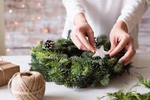 Female hands of unrecognizable woman decorating a wreath. Christmas composition.