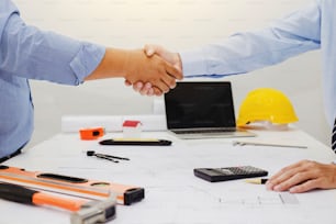 Architect and businessman shaking hands meeting discuss a plan about the construction project of real estate. Agreement and are willing to work together.