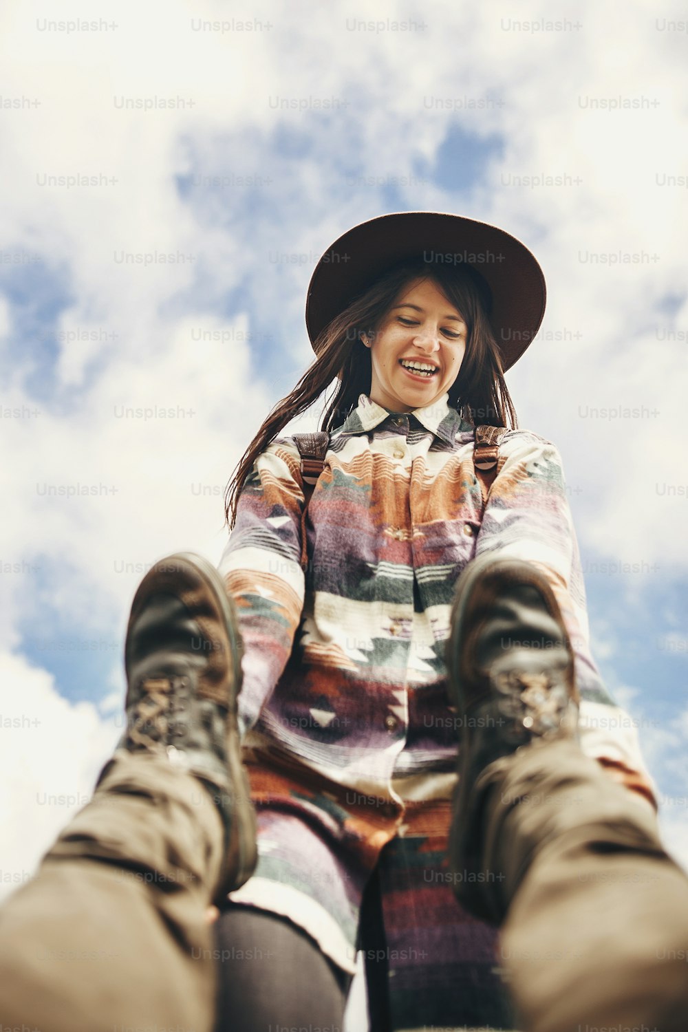 happy stylish traveler girl in hat holding man legs, and smiling, funny moment  of guy falling down on top of mountains. travel and wanderlust concept. space for text. couple traveling