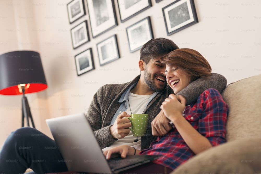愛の若いカップルは、ラップトップコンピュータでネットサーフィンをしています。男に焦点を合わせる
