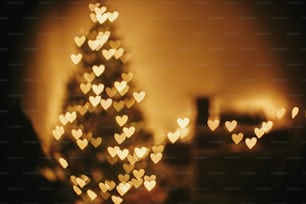크리스마스 추상적인 배경, 아름 다운 크리스마스 트리 황금 빛 빛 하트 보케. 축제 방에서 노란색으로 빛나는 조명의 흐림. 겨울 방학을위한 장식. 대기 순간