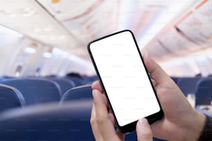 Airplane passenger using smart phone on plane. Businessman touching blank screen mobile phone at airplane. for graphics display montage.