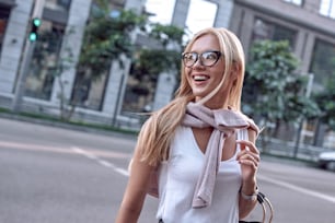 Profile of a beautiful businesswoman with glasses and handbag. She crosses the road and smiling