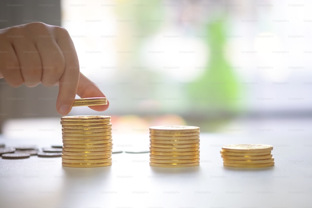 Concepto de ahorro de dinero preestablecido por monedas de pila de mano de niña para mostrar el ahorro de dinero para el futuro.