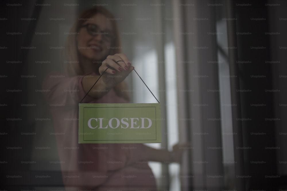 Store owner turning closed sign In shop doorway.