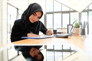 Islam Empresária que trabalha com papel de documento de finanças em mesa de madeira.