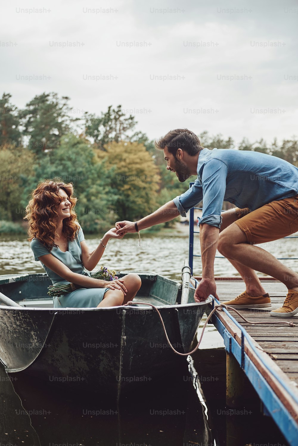 Feliz pareja joven que se prepara para remar en un bote mientras disfruta de su cita al aire libre