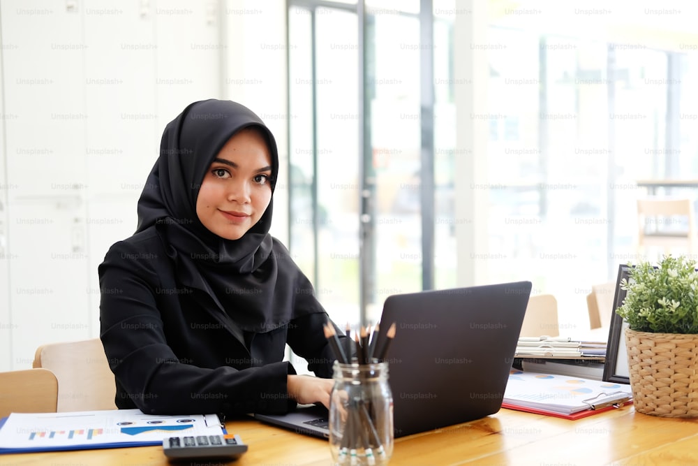 노트북 컴퓨터로 일하는 이슬람 여성, 사무실에서 일하는 사업가.
