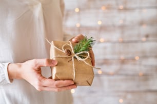 Unrecognizable young woman holding wrapped Christmas present.