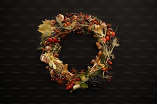 Autumn Wreath Flat Lay. Fall leaves circle with berries, nuts, acorns, flowers,herbs on black background top view. Seasons greetings. Space for text. Autumn mockup card.