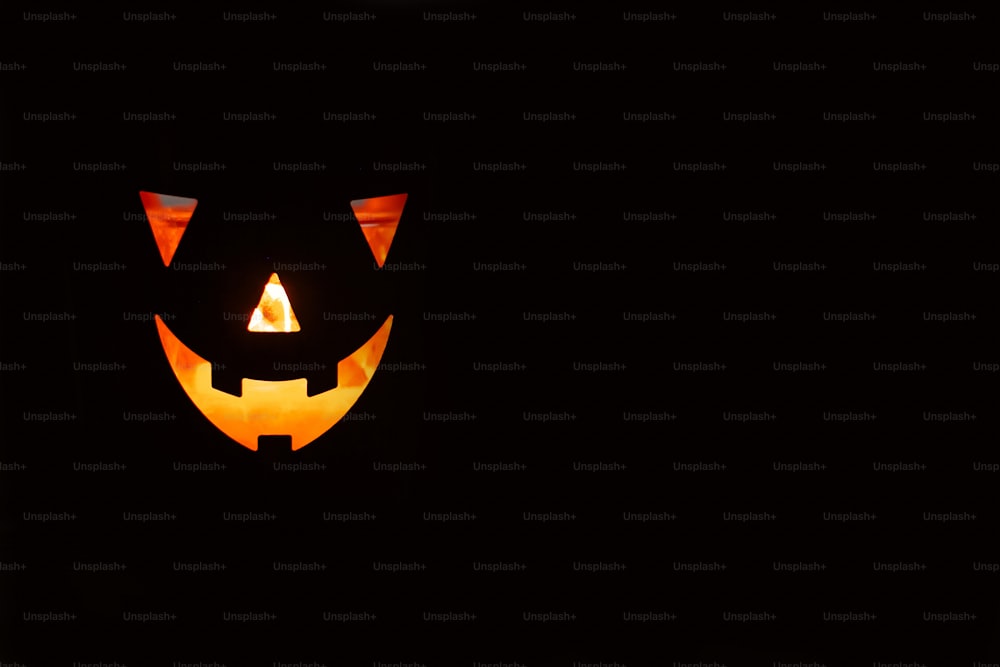 Zucca di Halloween con spaventosa faccia luminosa su sfondo nero isolata. Jack-o'-lantern zucca incandescente al buio. Dolcetto o scherzetto. Spazio per il testo. Mockup per halloween