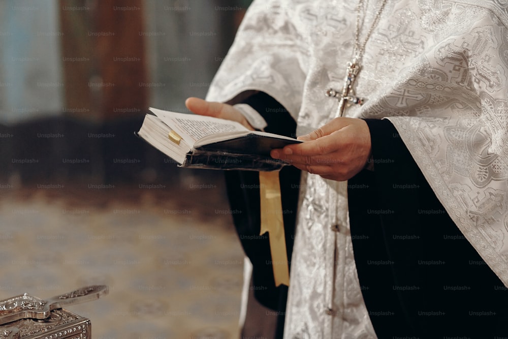 Priest reading holy bible in christian church during orthodox wedding ceremony, spiritual ritual concept