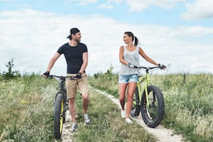 Young couple resting after bike ride in field by fatbikes