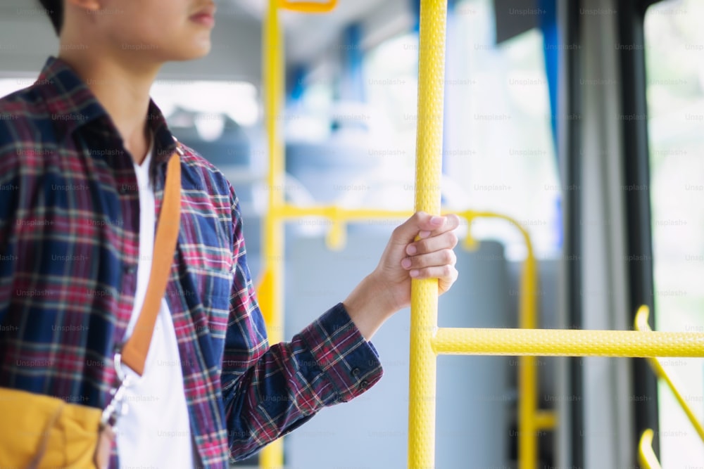 Young asian man holding handle of the public bus.