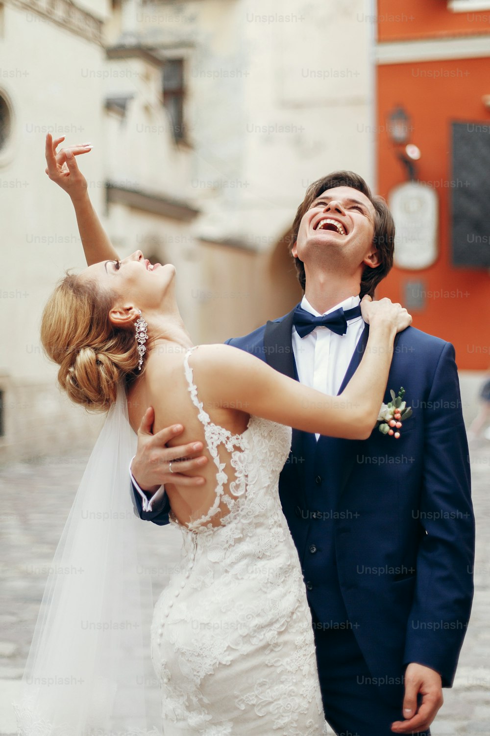 Emotional couple portrait, happy, smiling bride and groom hugging and laughing outdoors, unique wedding moment