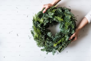 Female hands holding green Christmas wreath. Top view. Copy space.