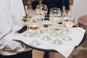 glasses of champagne or wine on tray. waiter serving champagne at wedding reception in restaurant. luxury catering. christmas celebration, drinks at feast