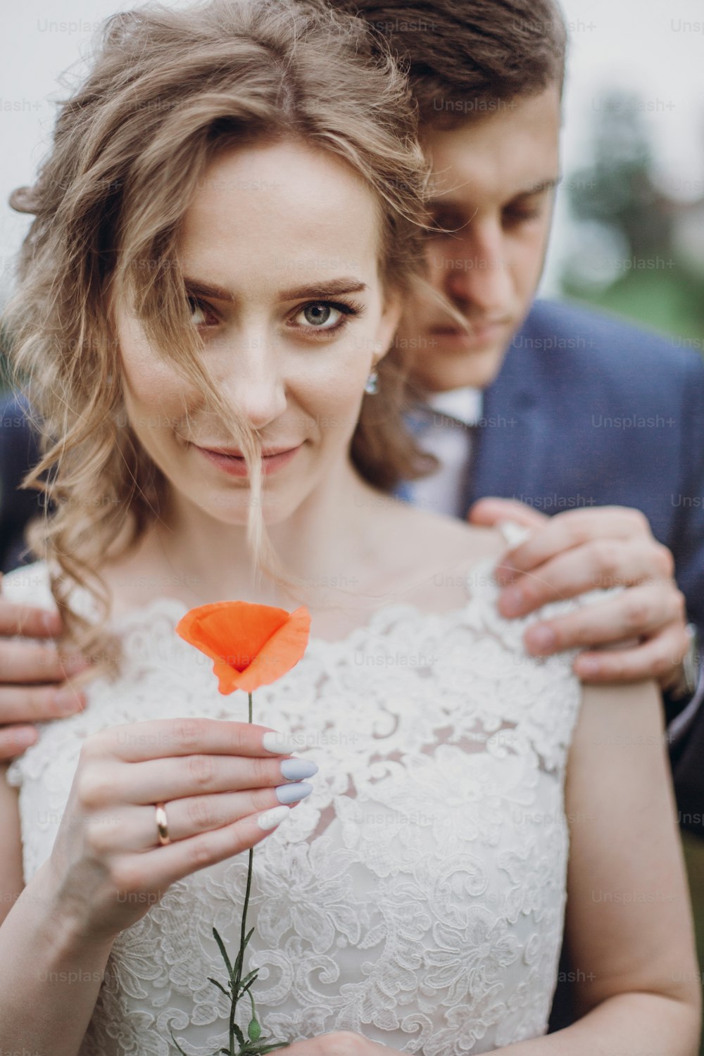Bräutigam umarmt schöne wunderschöne Braut mit Mohnblume. Glückliches sinnliches Hochzeitspaar, das sich in Liebe umarmt. Glückliche romantische Momente. Elopement-Konzept. Platz für Text