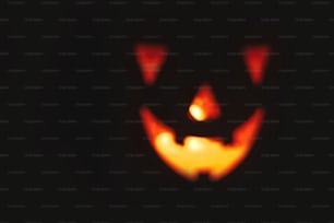 Halloween Kürbis mit gruselig leuchtendem Gesicht auf schwarzem Hintergrund isoliert. Jack-o'-Laterne leuchtender Kürbis im Dunkeln. Süßes oder Saures. Platz für Text. Kulisse für Halloween. Unscharfes Bild