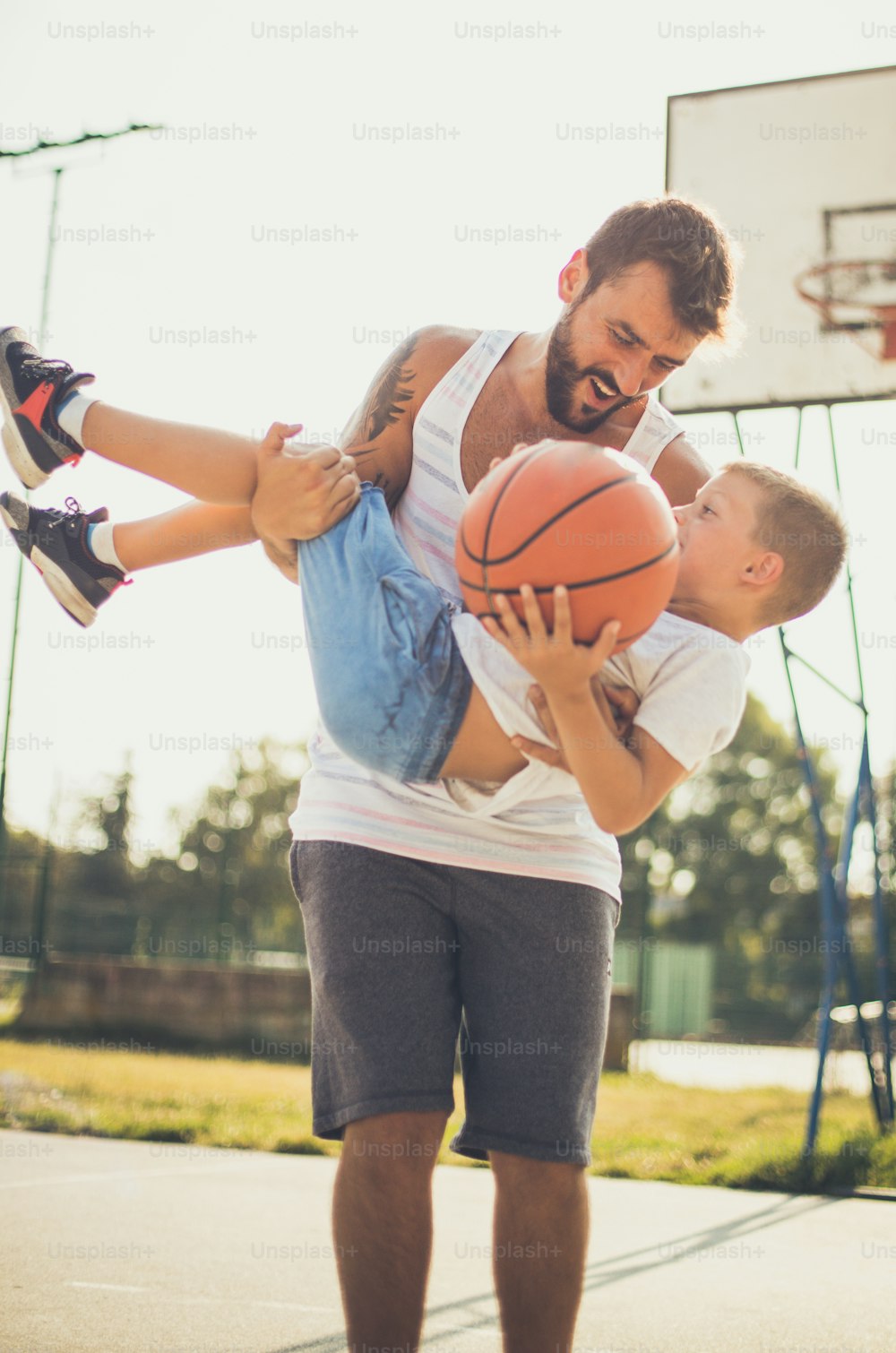 Summer is a time for sports games. Father and son on basket court.
