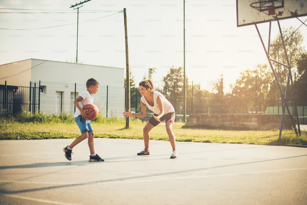 Time for play. Mother and son playing basketball.