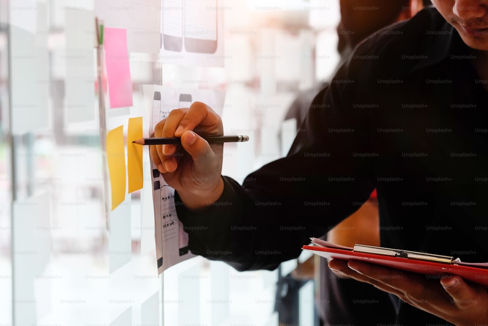 A man working with creative and using stocky note paper on glass wall.