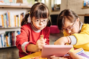 Rehabilitation center. Two dark-eyed sisters wearing glasses studying in rehabilitation center