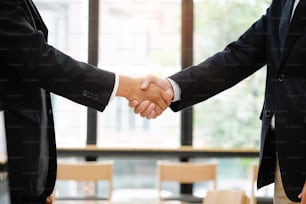 Concept d’acquisition d’entreprise, un homme d’affaires recadré se serrant la main à la fin d’une réunion.