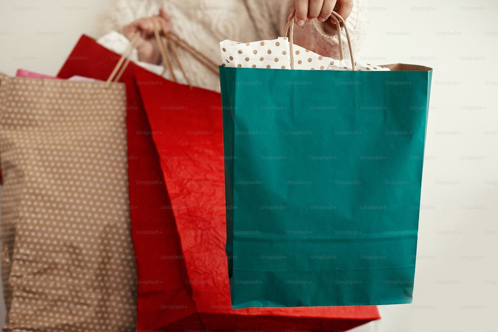 크리스마스 쇼핑 및 계절 판매. 흰색 배경에 화려한 쇼핑백을 들고 있는 행복한 소녀. 크리스마스 세일. 텍스트를 위한 공간입니다.  블랙 프라이데이. 사이버 먼데이