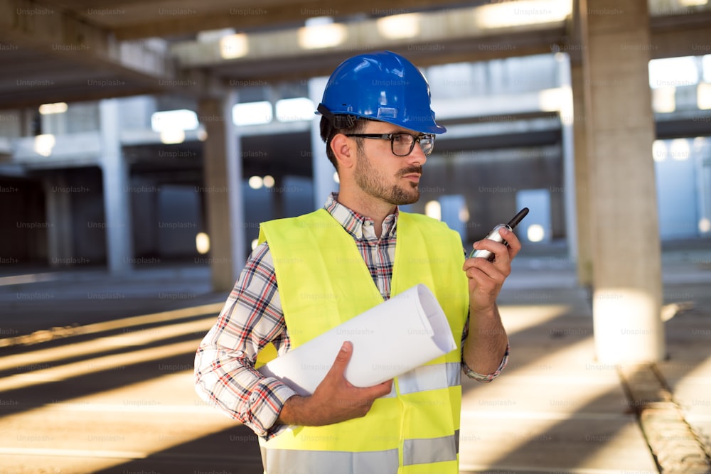 Male architect communicating on walkie-talkie at building site