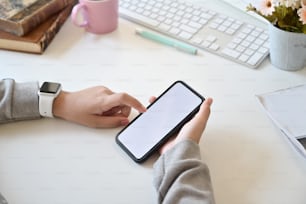 Blank screen mobile phone in female hand on desk work in home office