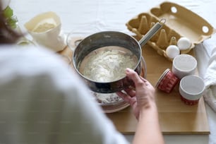 Cooking Christmas chocolate muffins. Mixing ingredients for brownies, cupcakes, pancakes. Woman hands preparing dough for dessert. Selective focus. Back view