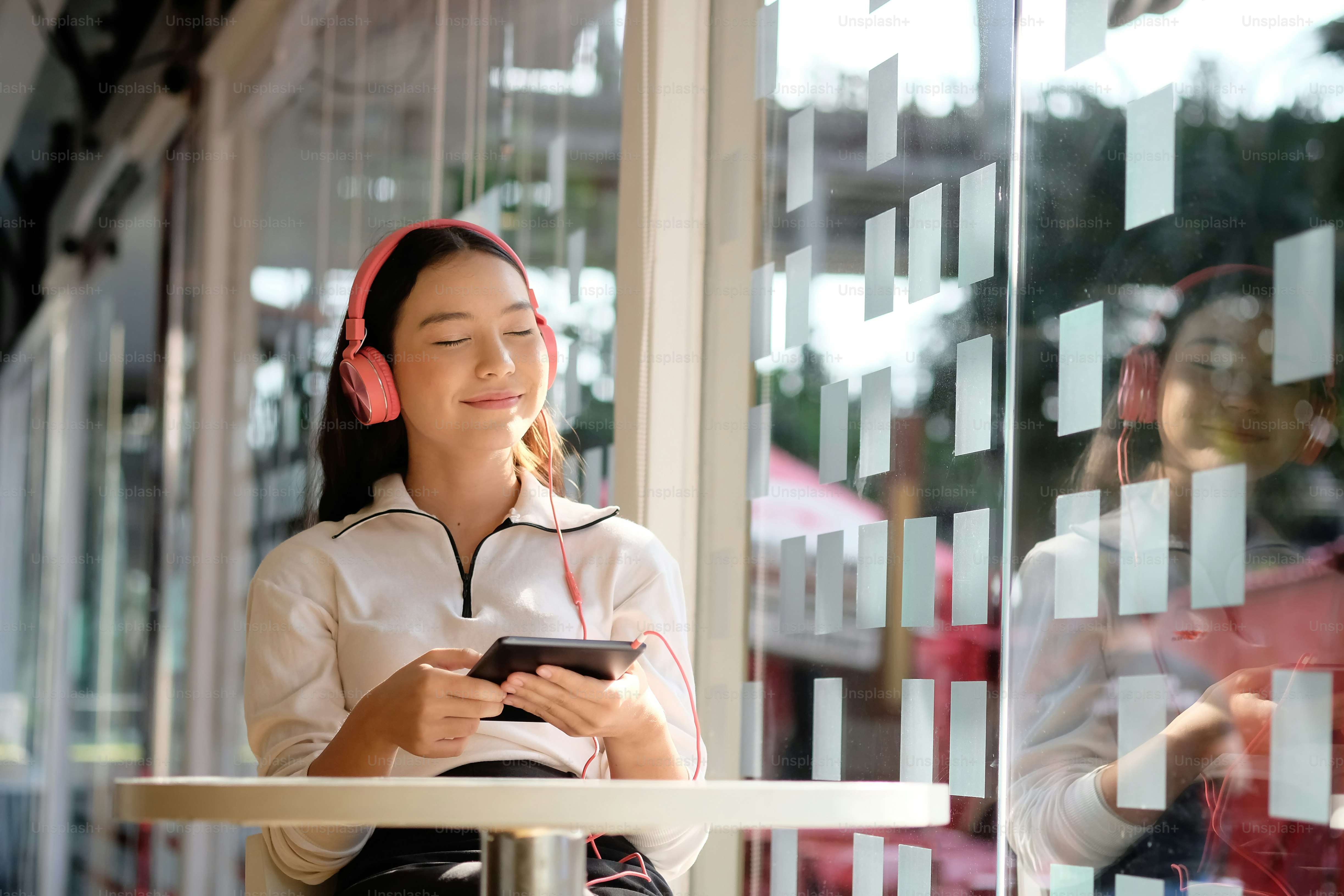Remaja wanita mendengarkan streaming musik dengan headphone.