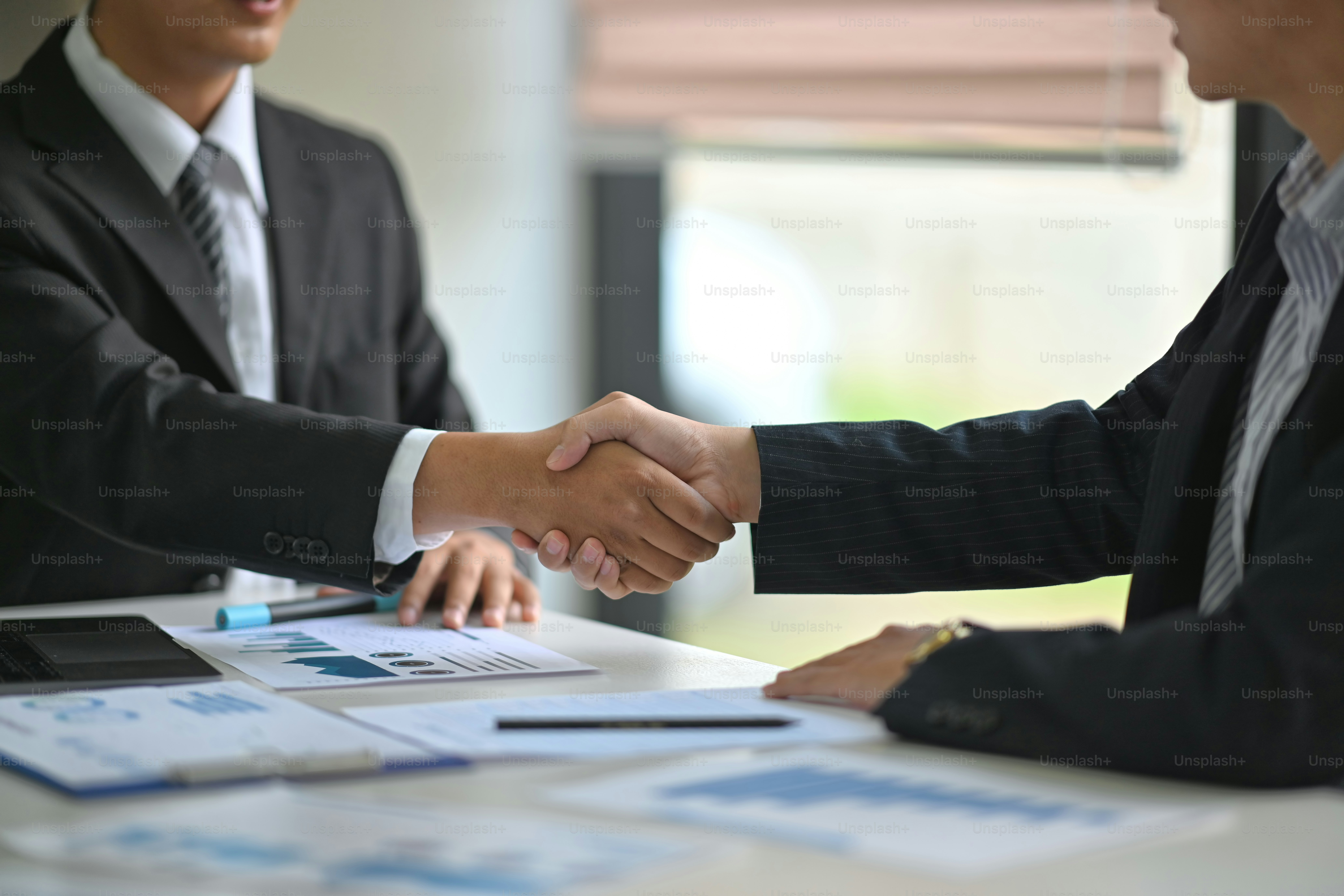 Cropped shot of two businessmen shaking hands in meeting room
