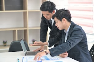 젊은 아시아 사업가가 동료의 정보 서류 작업을 돕고 있다.