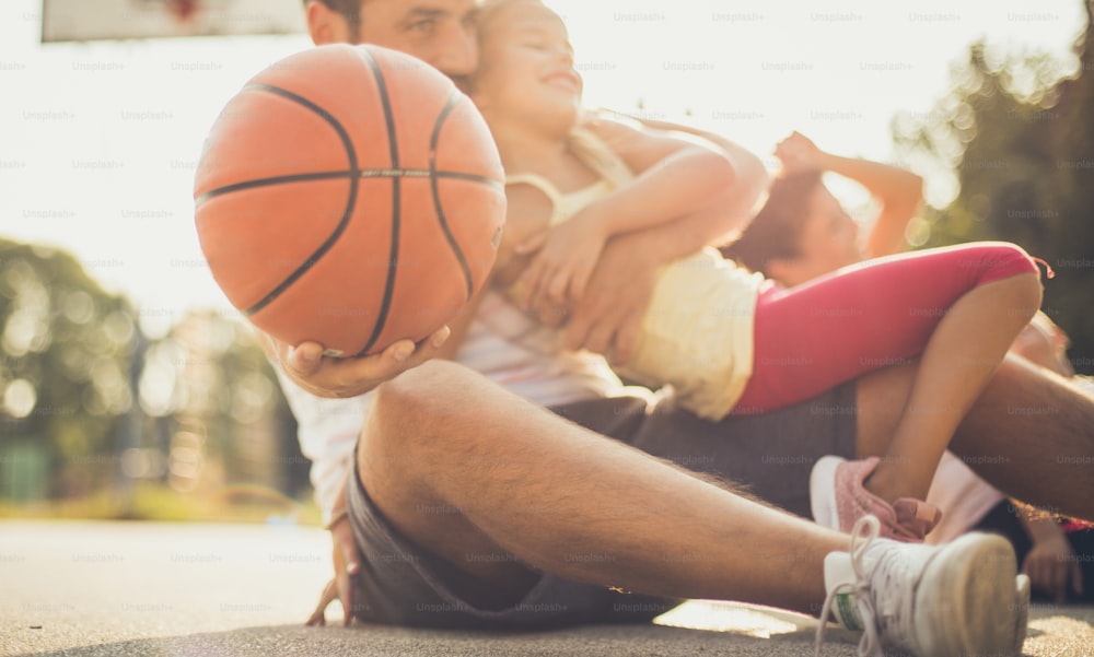 Let's bring sport into our lives. Father and daughter on basketball playground. Focus on ball. Close up.