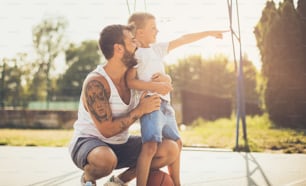 Dad, let's go to that playground. Father and son on basket court.