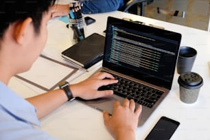 Un programador masculino que trabaja con una computadora portátil y codifica en la computadora.