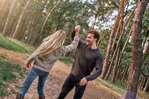 秋の森でポーズをとる愛の屋外の幸せなカップル。若い女性と男性が屋外で踊っている
