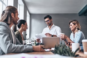 Group of young modern people in smart casual wear discussing business while working in the creative office