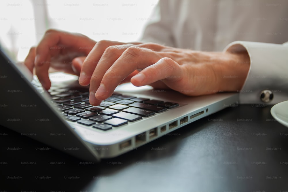 Business man using laptop computer. Male hand typing on laptop keyboard