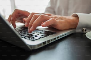 Hombre de negocios usando computadora portátil. Mano masculina escribiendo en el teclado de la computadora portátil