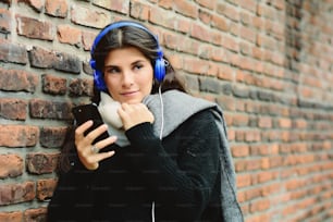 음악을 듣고 스마트폰을 사용하는 아름다운 젊은 여성. 기술 개념입니다. 도시 장면