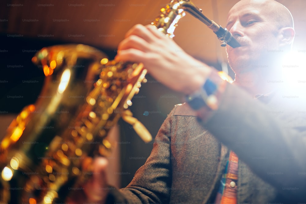 Close up of saxophonist playing his instrument. Back light.