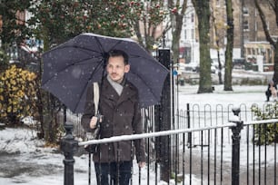 Retrato de un joven guapo con paraguas en la calle de Londres en la nieve del invierno