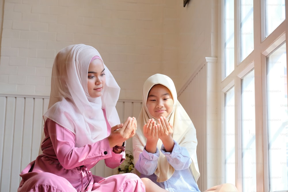 Children learning muslim praying with adult woman.